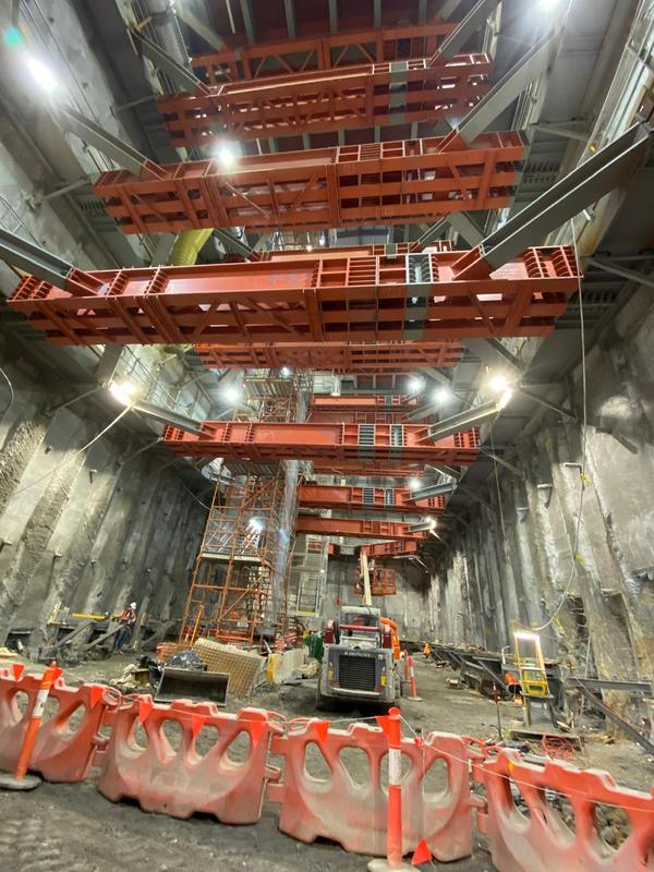 Base of the shaft with a skid steer, reinforcement mesh and a scaffold stair beneath tiers of red steel props