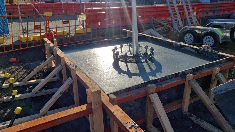Freshly poured concrete footing in timber formwork with a cast-in anchor bolt cage
