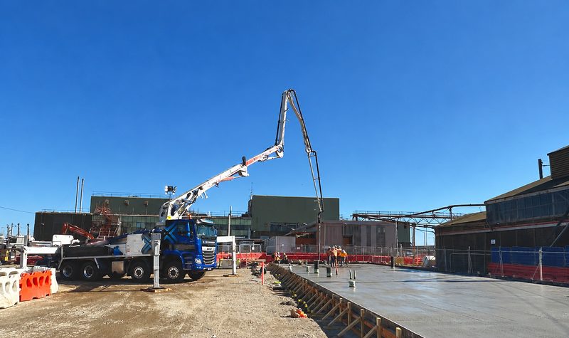 Concrete pump boom placing concrete for a large slab at a rail maintenance facility